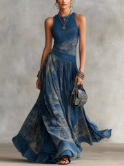 Dusty blue printed sleeveless maxi dress with round neck and flowing patterned skirt worn standing