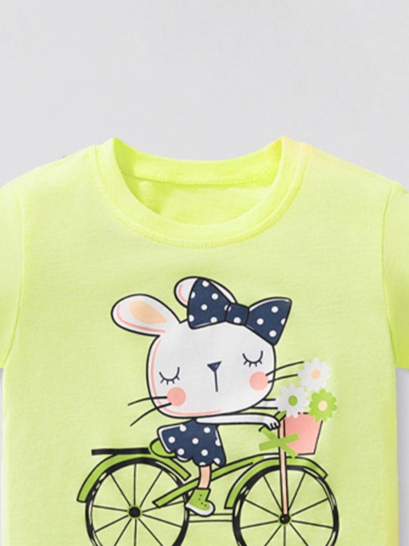 Upper front view showing the round neckline and rabbit bicycle graphic on the yellow green t-shirt