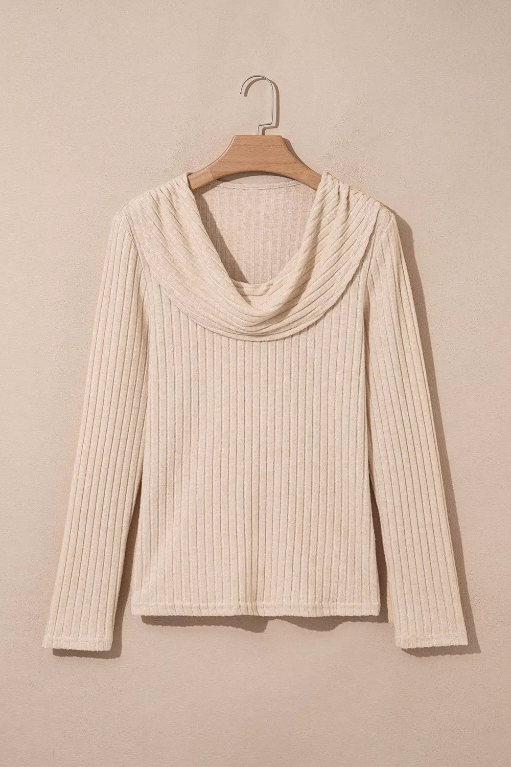 Cream ribbed long-sleeve top with a draped cowl neckline hanging on a wooden hanger