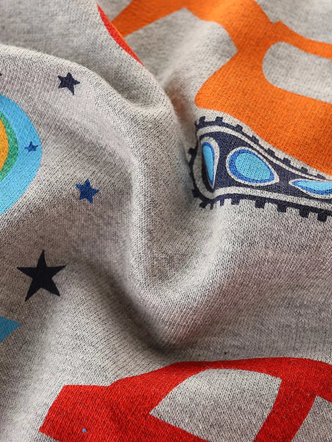Close up of light gray children's sweatshirt fabric with stars excavator track and car prints