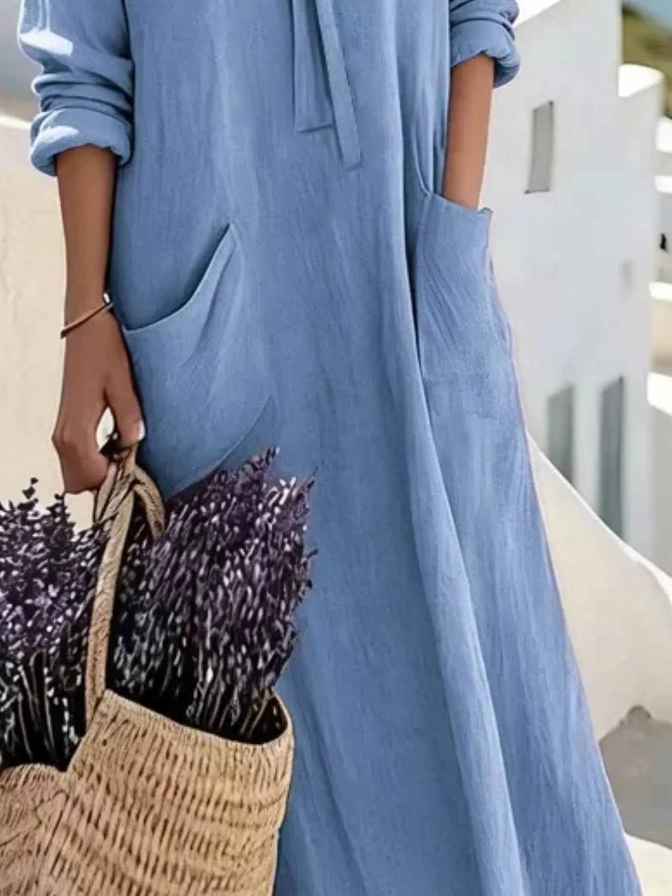 Cropped view of sky blue long sleeve loose maxi dress, showing pockets and flowing skirt