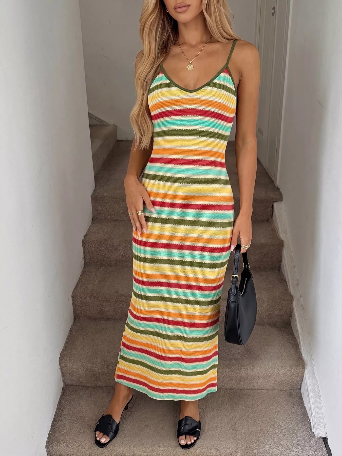 Front full view of multicolor striped bodycon knit midi dress on stairs holding a bag