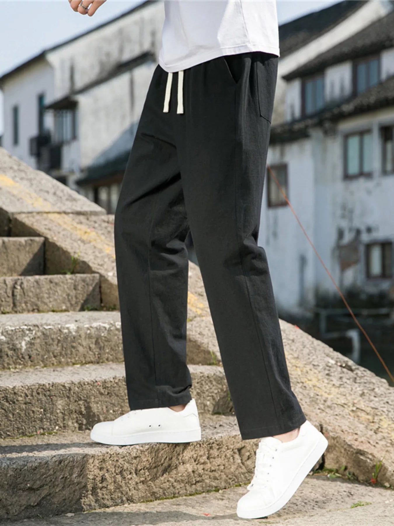 Men's black loose-fit casual pants with a drawstring waist and pockets.