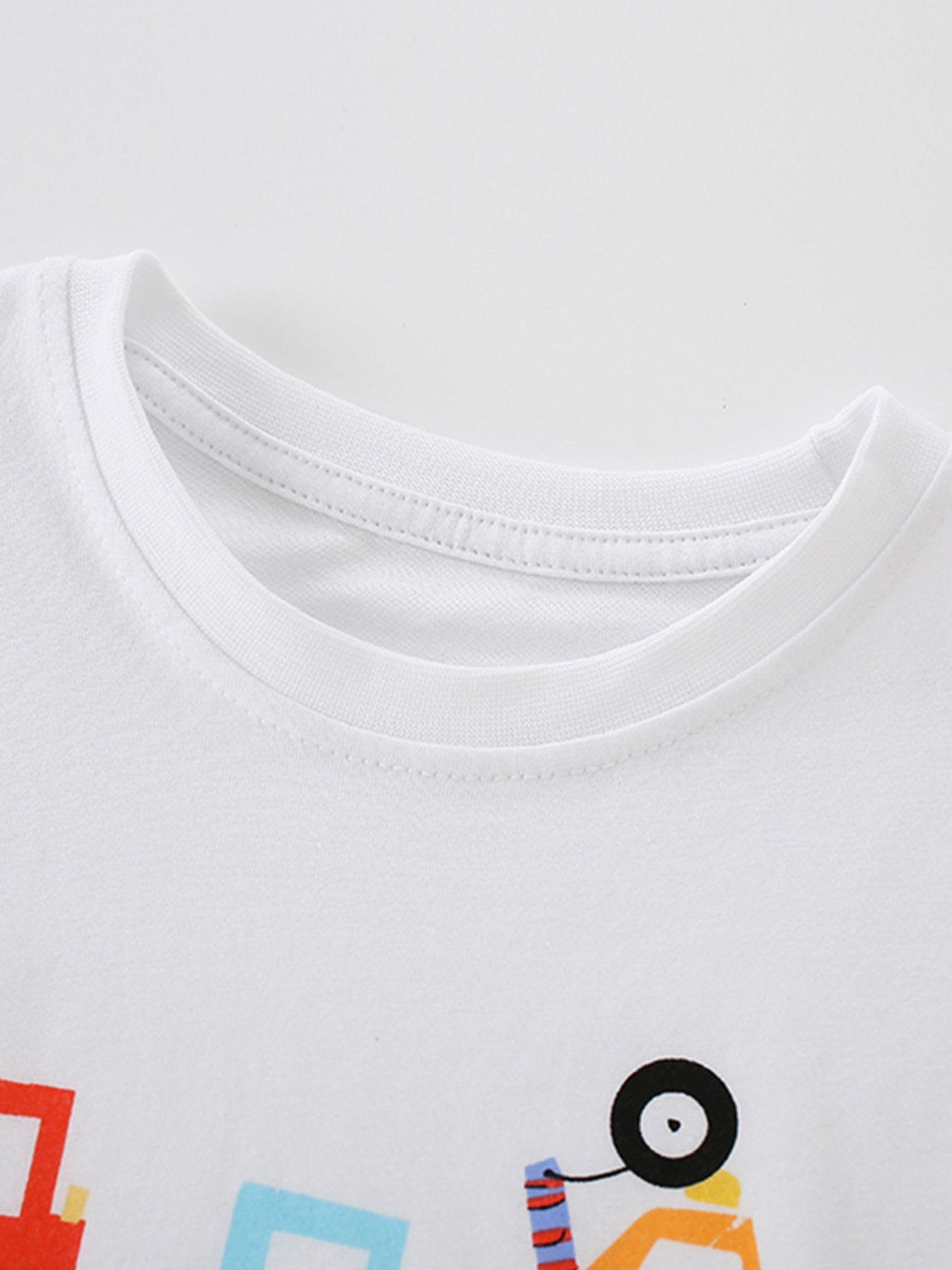 Detail view of the ribbed crew neckline and stitching on a children's white construction vehicle t-shirt