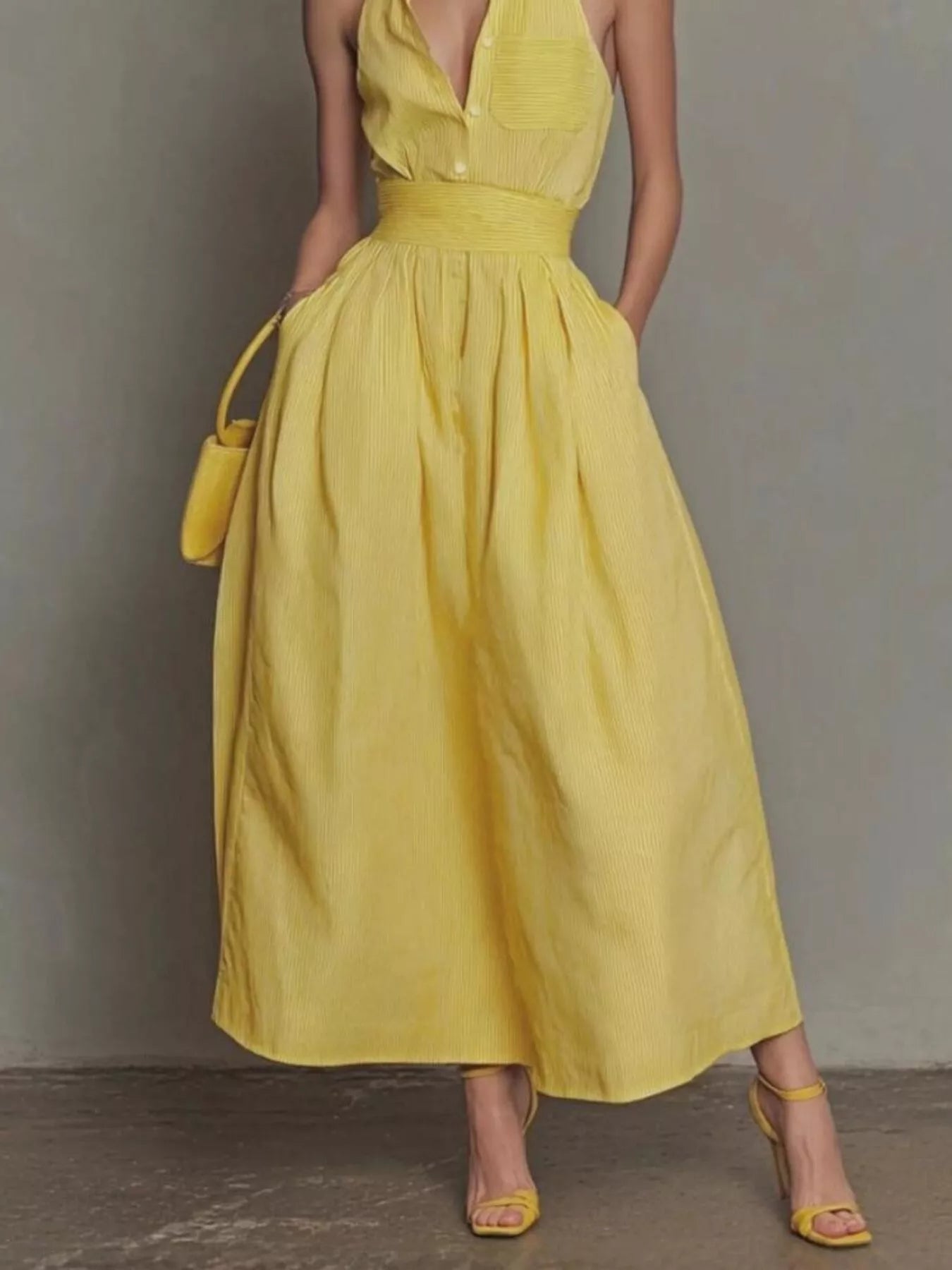 Lower front view of yellow sleeveless maxi dress showing wide waistband and side pockets