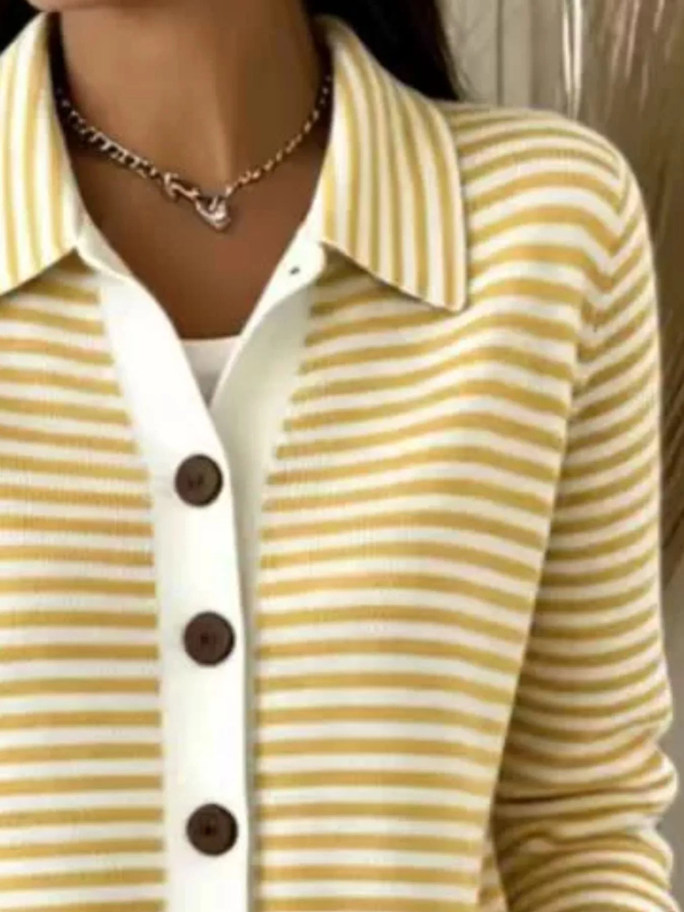 Close-up on-model view of yellow and white striped collared cardigan with brown buttons