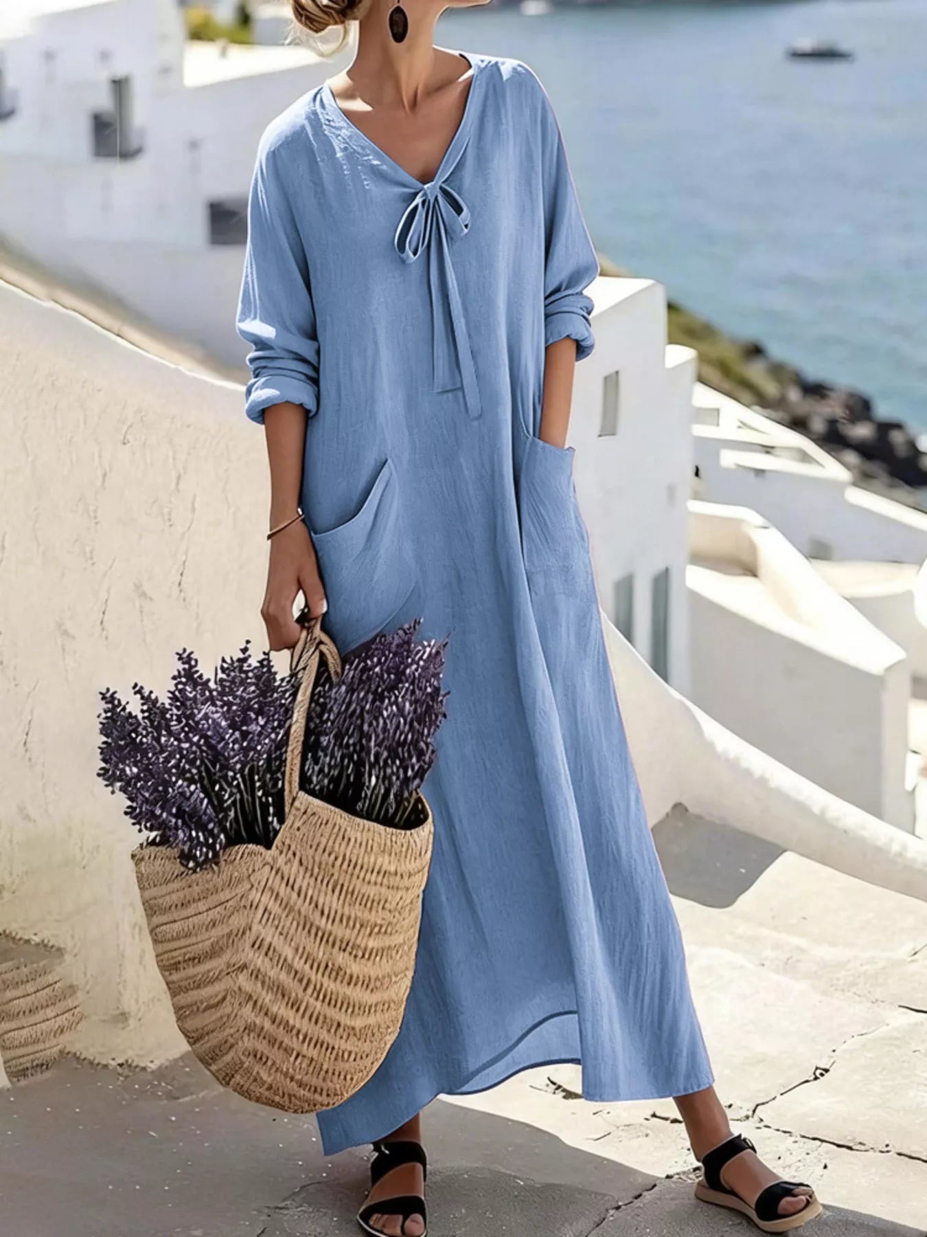 Model wearing sky blue long sleeve loose maxi dress outdoors, full view with large pockets and tie neck