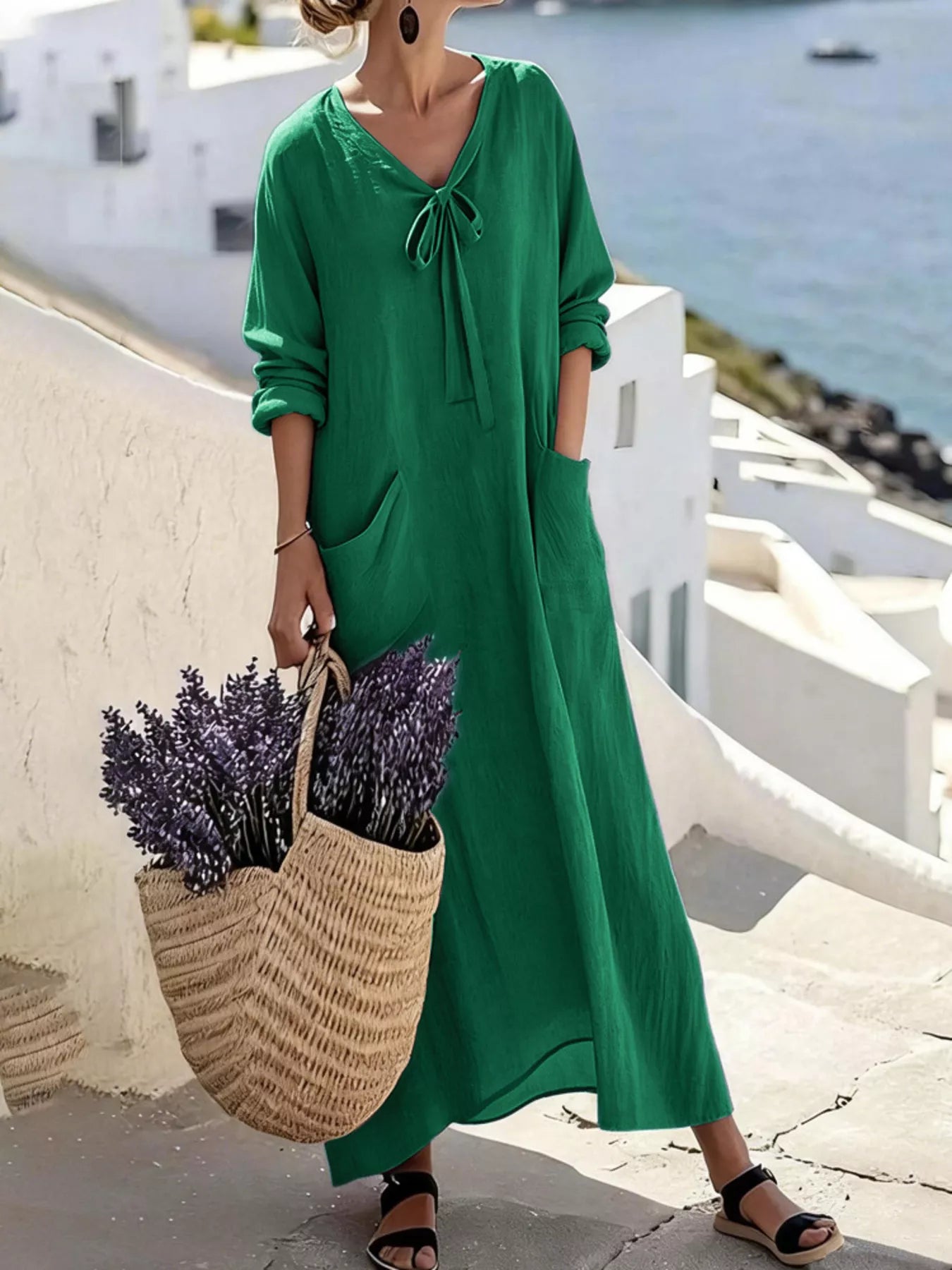 Model wearing green long sleeve loose maxi dress outdoors, full view with large pockets and tie neck