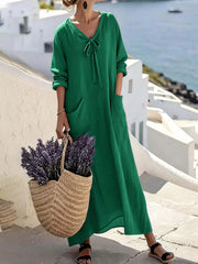 Model wearing green long sleeve loose maxi dress outdoors, full view with large pockets and tie neck