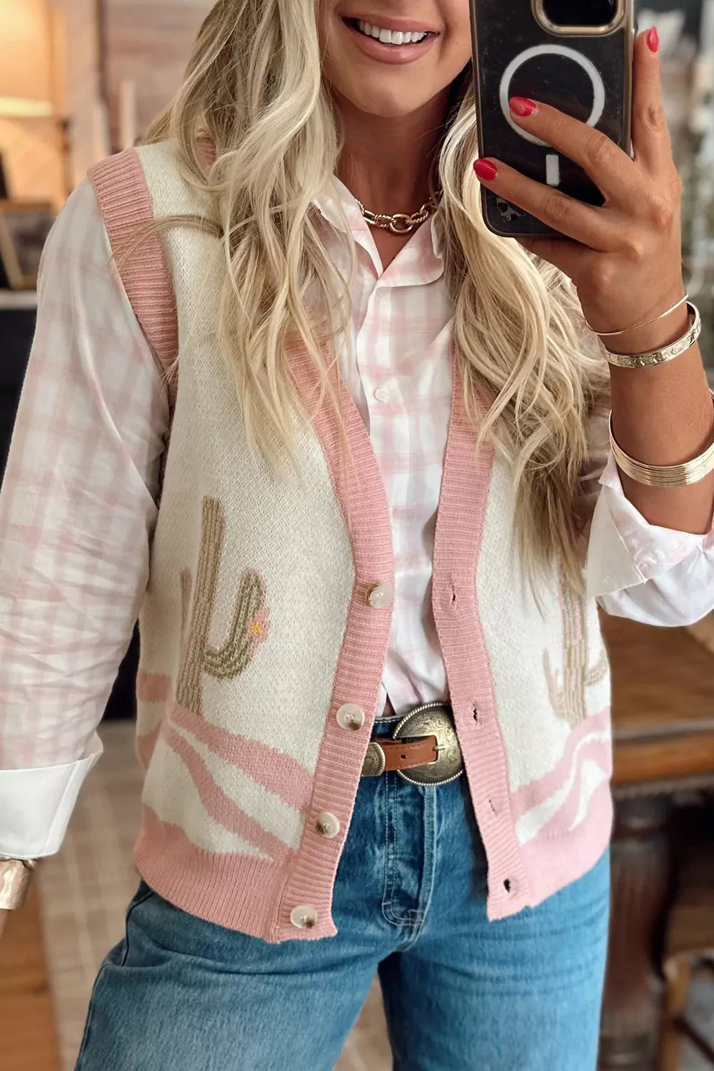 Mirror selfie front view of the cream cactus sweater vest with pink trim over a pink check shirt