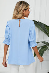 Back view of light blue blouse with pleated flounce sleeves and a keyhole neckline.