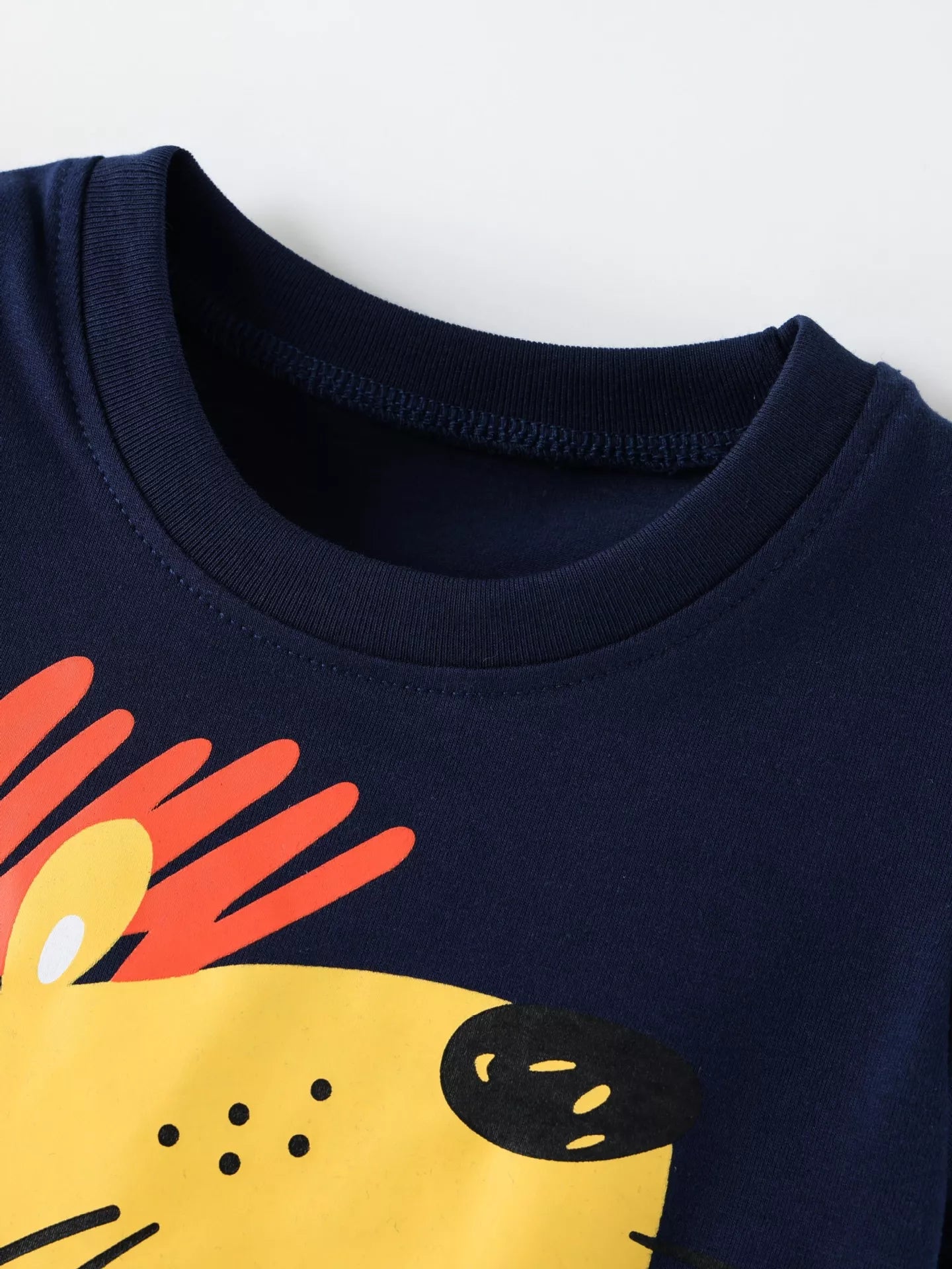 Close up of the dark blue round neckline and the top of the yellow lion graphic