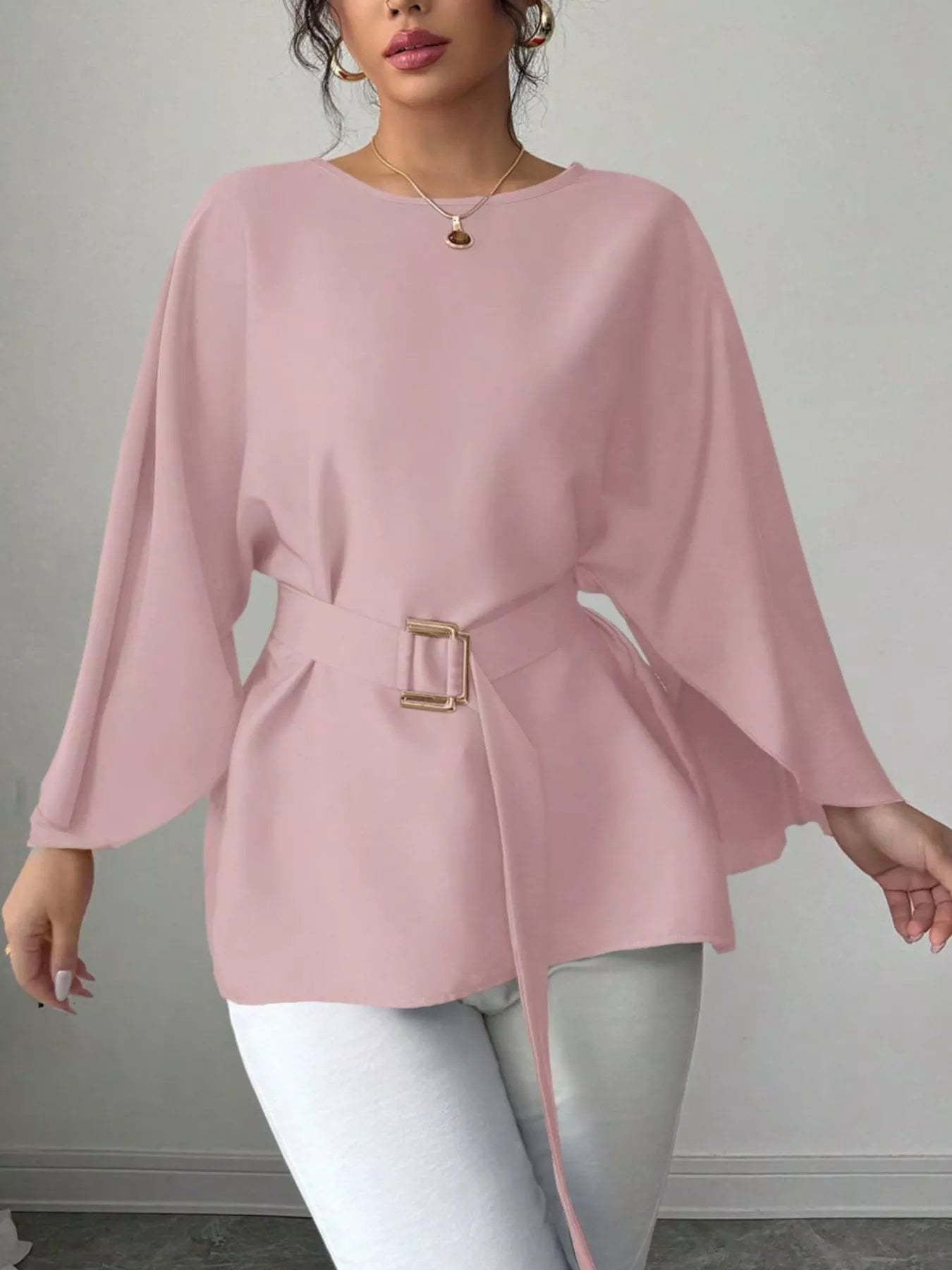 Pink batwing sleeve blouse front view with arms extended showing flowing sleeves and belted waist