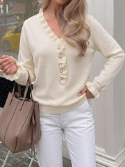 Cream V neck knit top with ruffle trim and pearl buttons shown front on