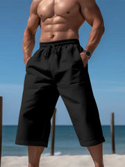 Men's black cropped casual pants with a drawstring waist and pockets.