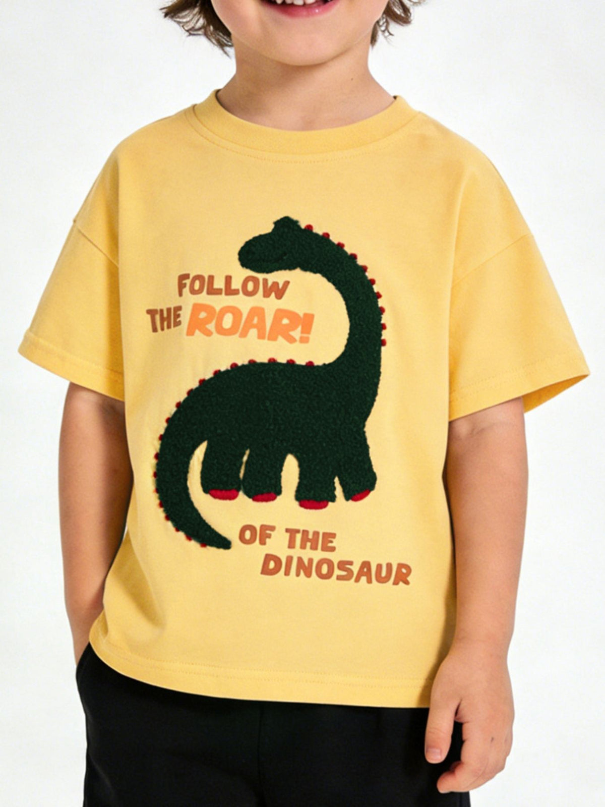 Children's yellow round neck T-shirt with a dark green textured dinosaur graphic, shown worn in front view