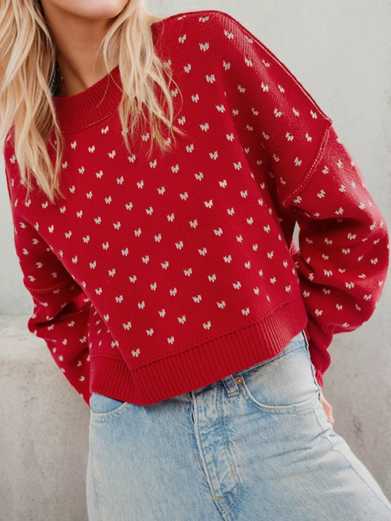 Close front view of the red dotted sweater showing dropped shoulders and ribbed hem