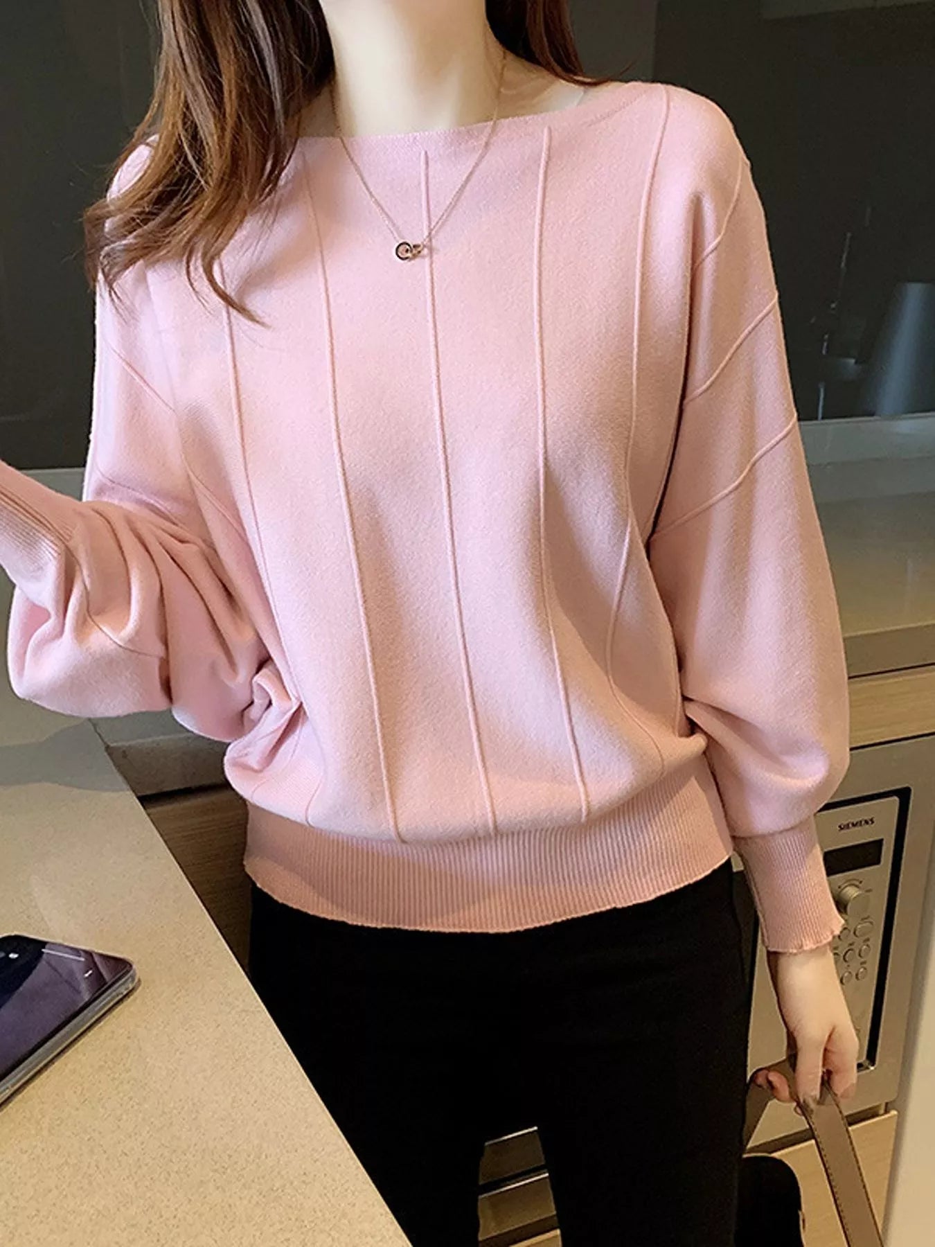 Close front view of the blush pink batwing sleeve knit top with vertical seams and ribbed hem.