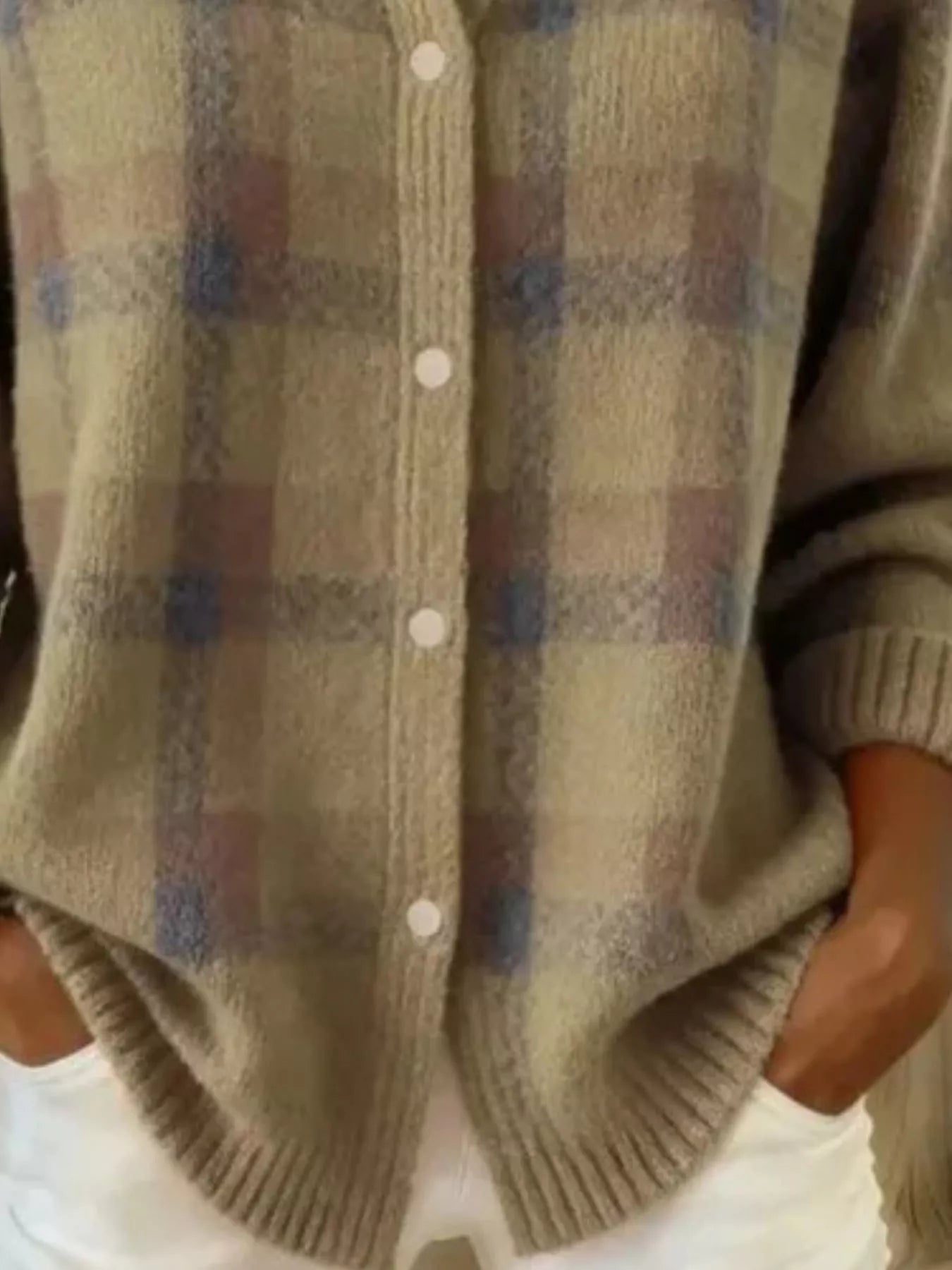Close-up of the lower front and ribbed hem of a khaki plaid knit cardigan with white buttons