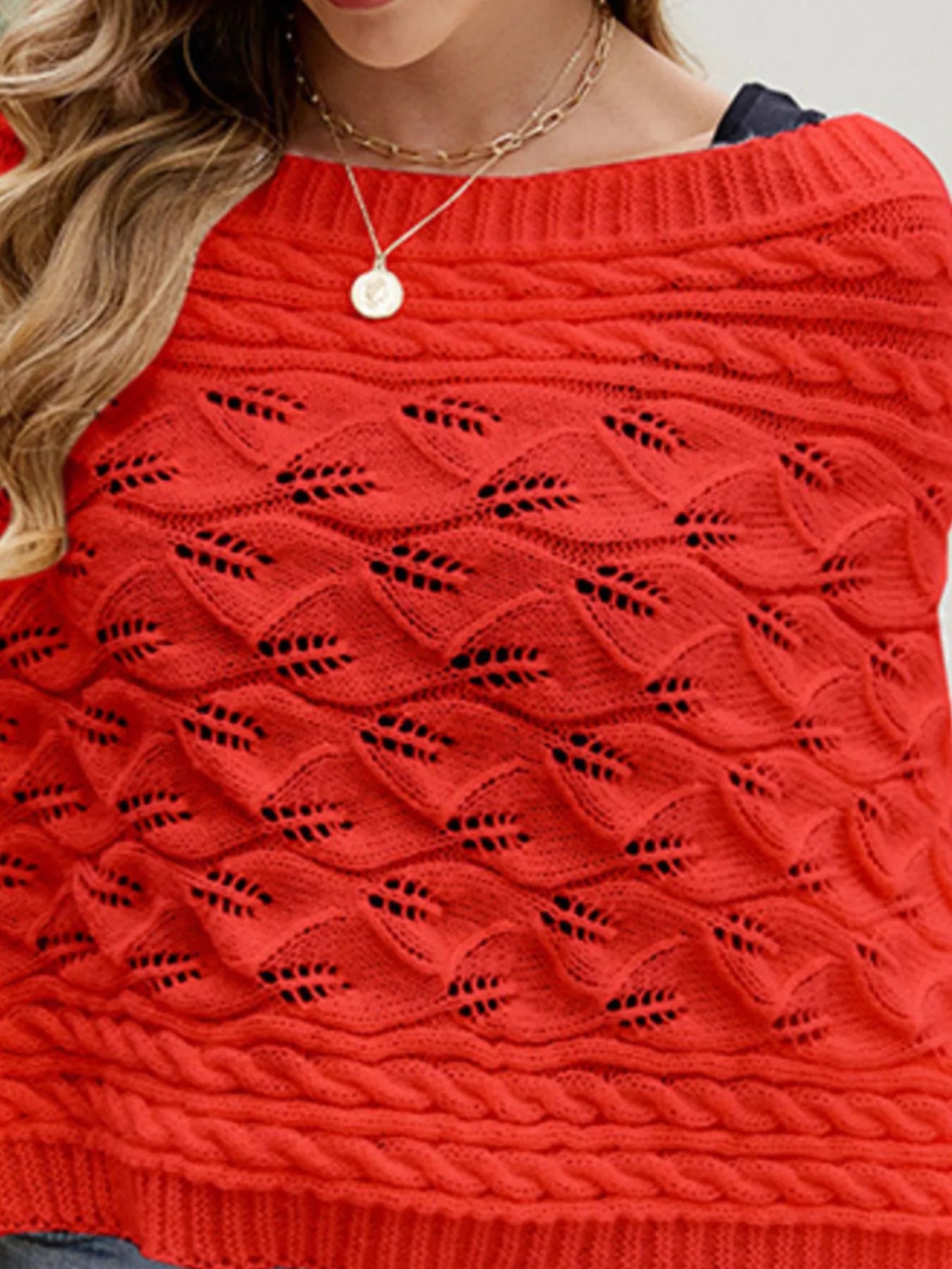 Close up of red batwing sweater with cable and leaf openwork knit texture.