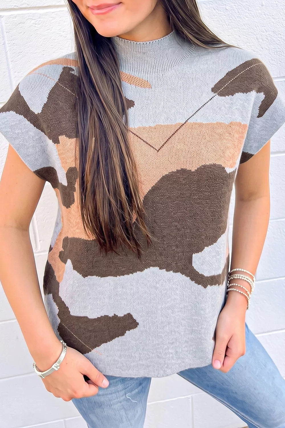Front view of a gray, brown, and tan camouflage knit top with high neck.