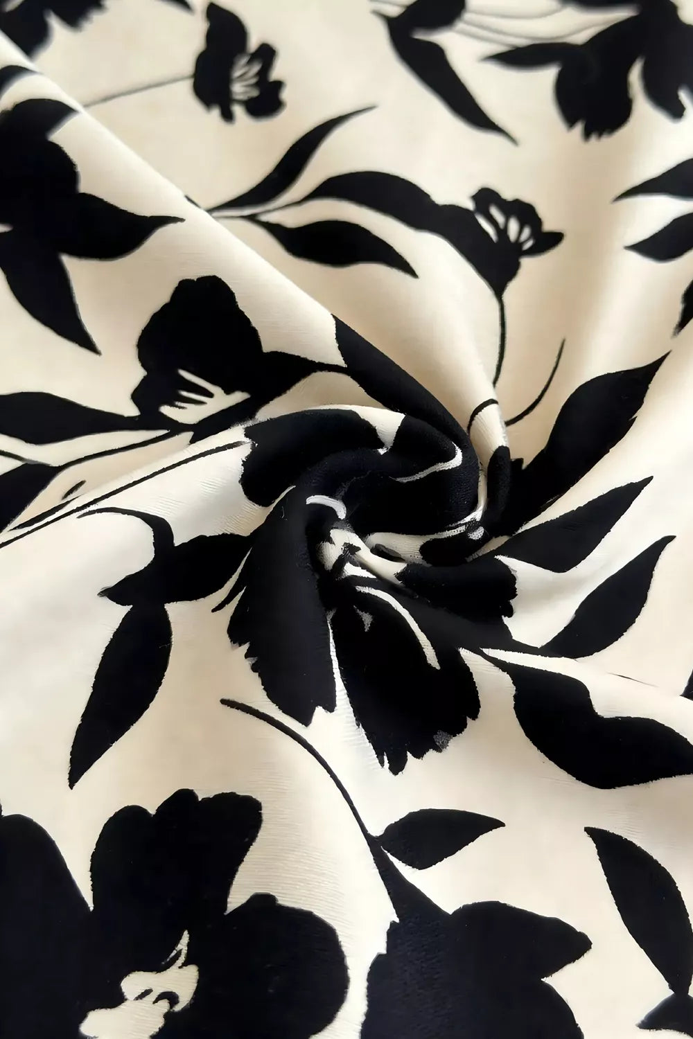Close detail view of khaki floral fabric with large black flowers and leaves