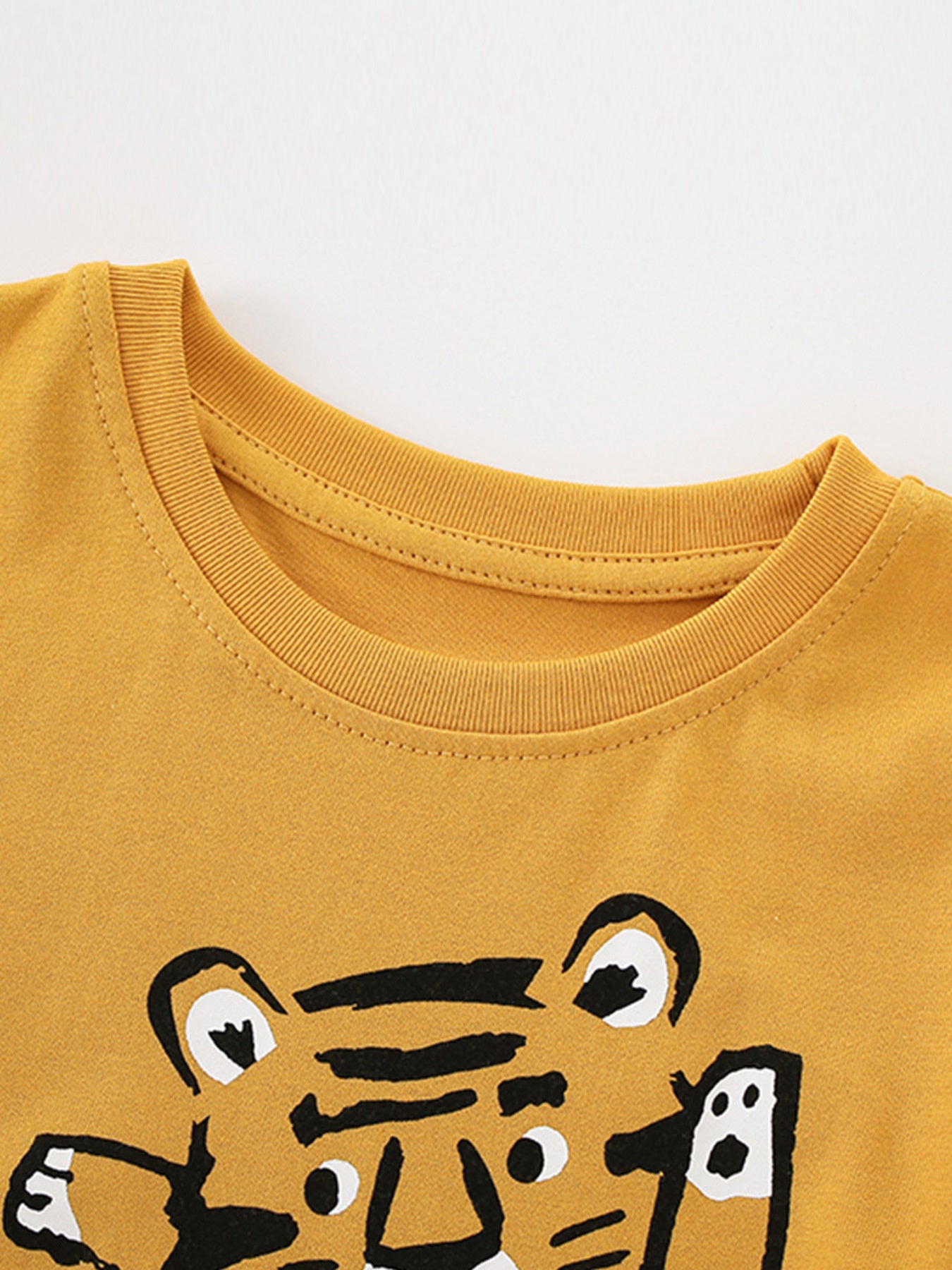 Close-up of the ribbed round neckline and stitching on the children's mustard t-shirt