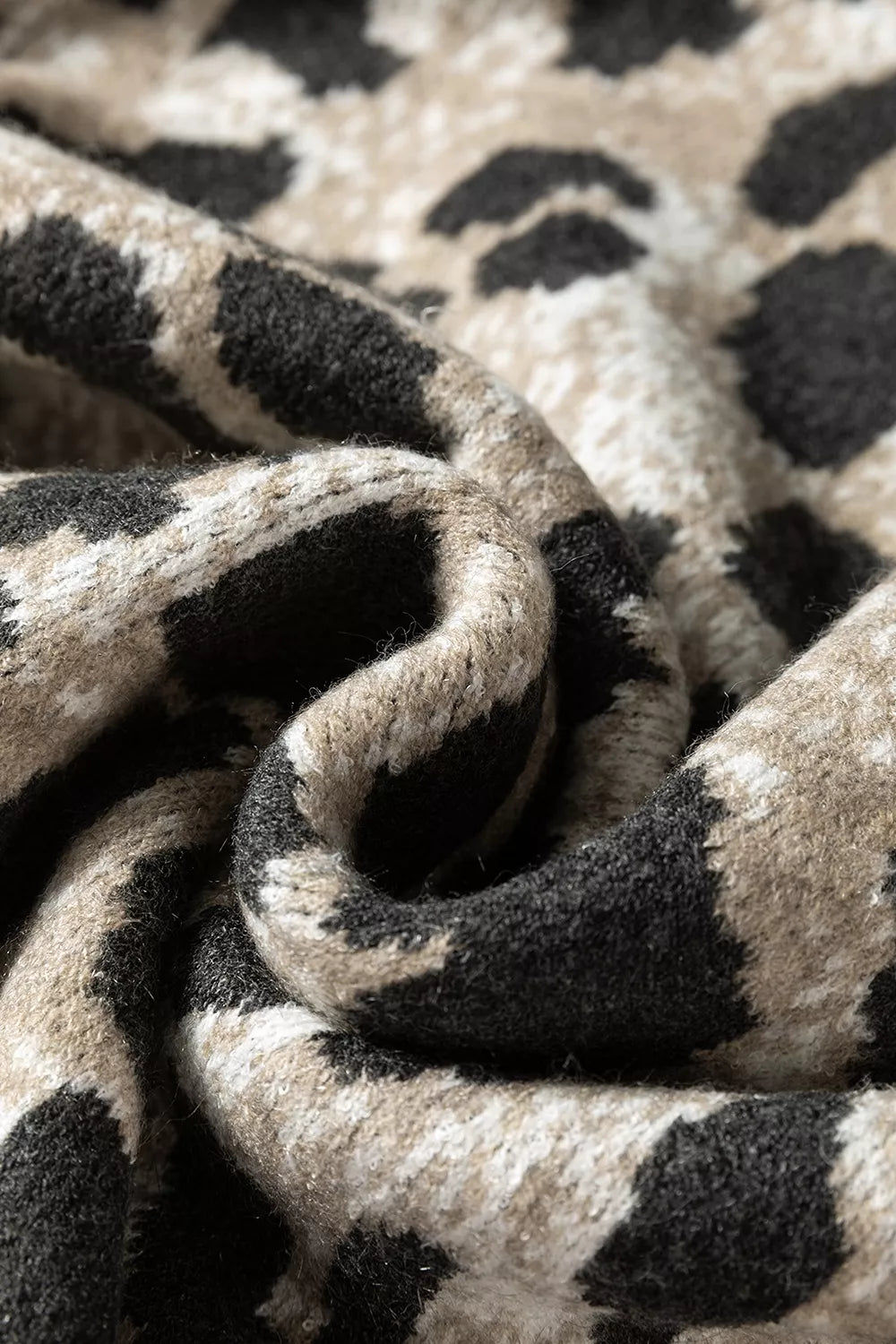 Close up of the folded gray and black leopard print knit fabric showing its texture.