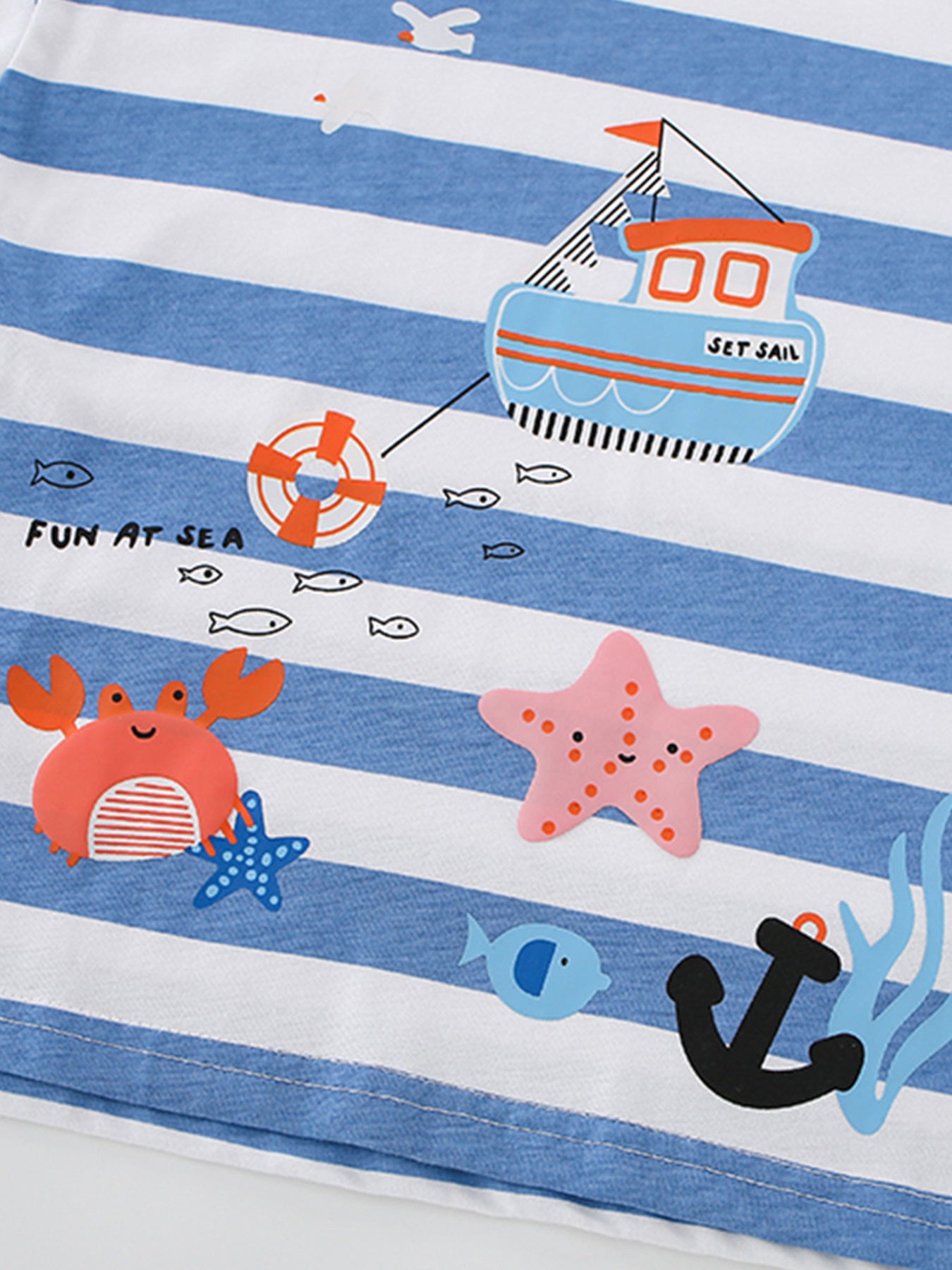 Close-up of the boat, crab, starfish and anchor prints on a blue and white striped children's T-shirt