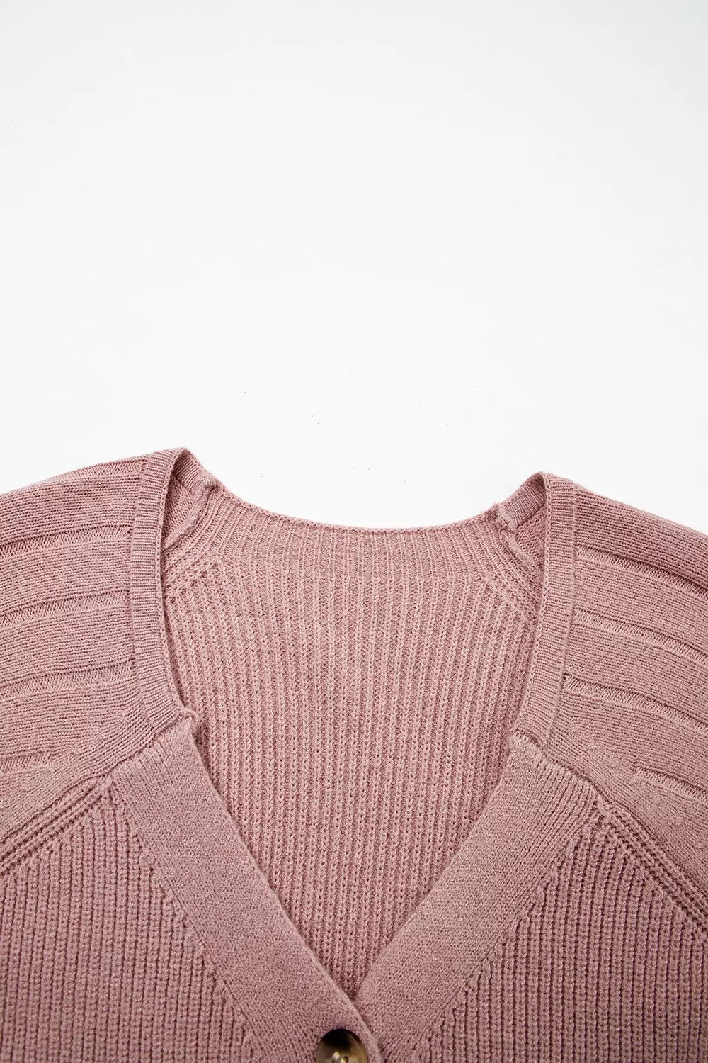 Flat lay close-up of the V-neckline and ribbed knit on a dusty pink cardigan