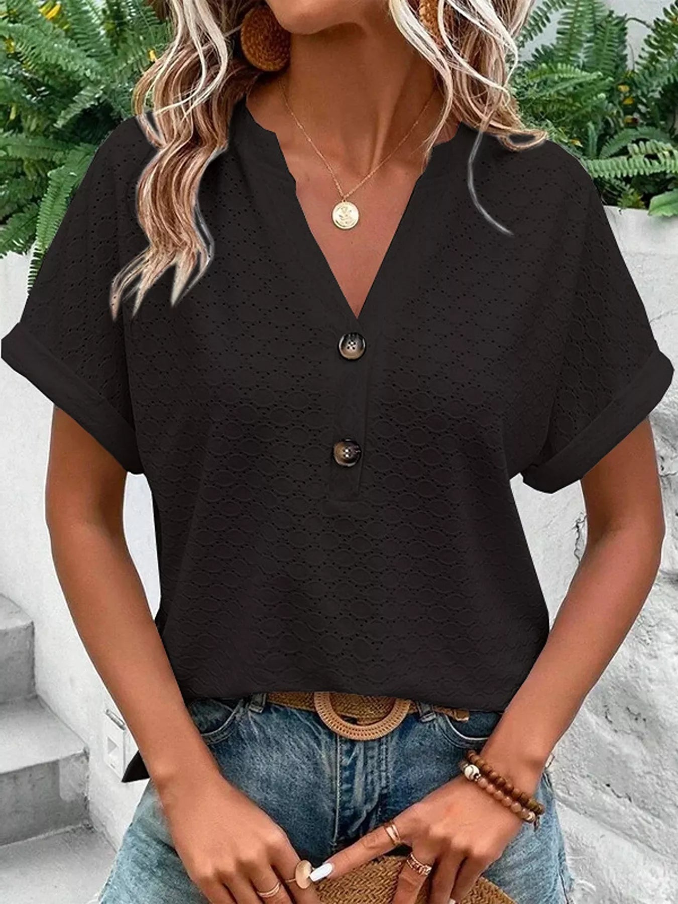 Black notched short-sleeve top with eyelet texture, button front, and rolled cuffs on a model