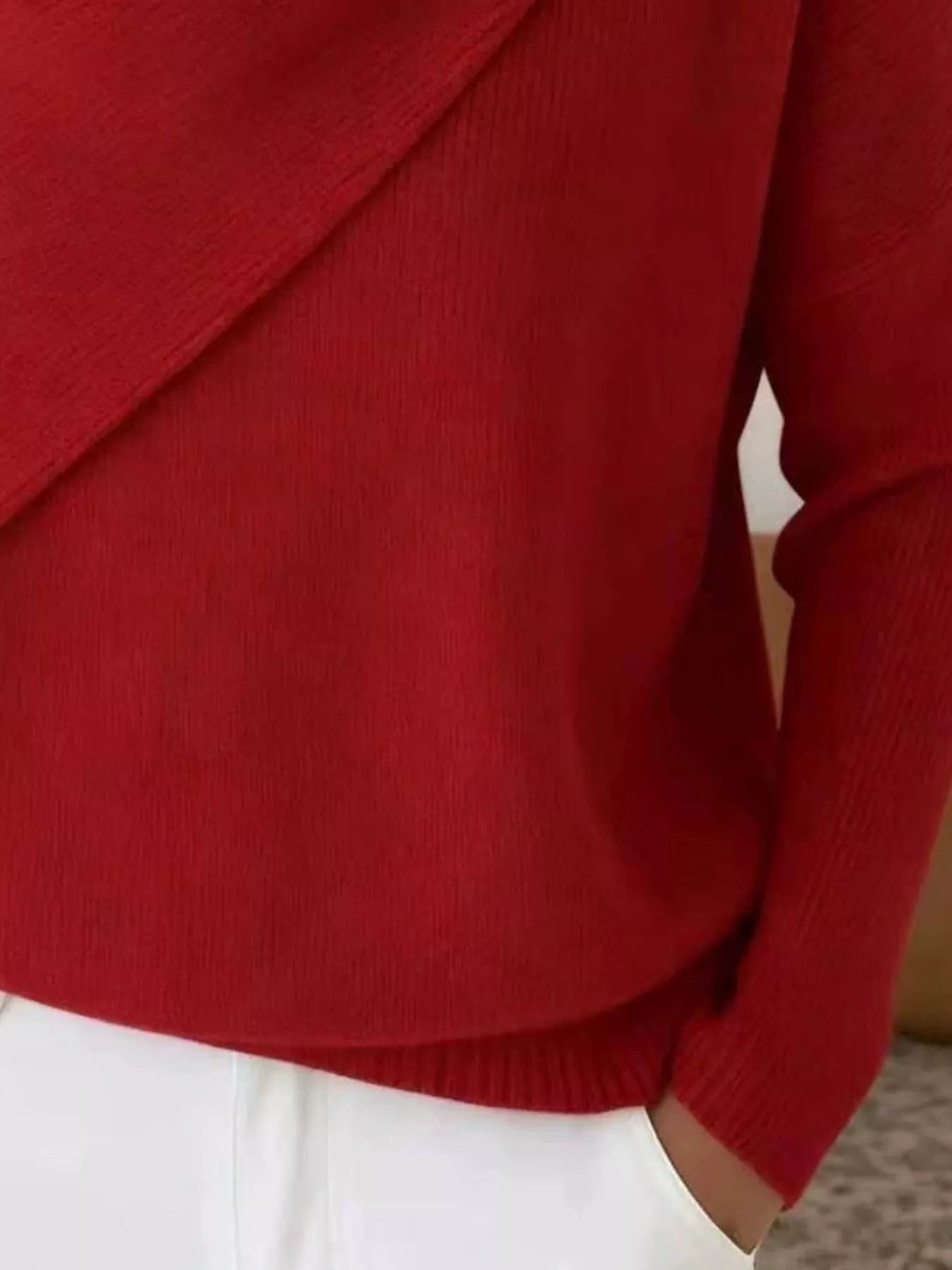 Close-up of the red sweater lower body and long sleeve showing the ribbed hem and knit texture