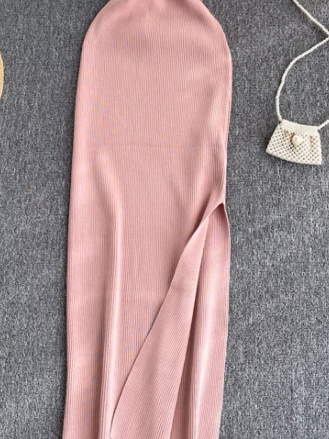 Lower skirt of pink ribbed knit midi dress showing side slit detail