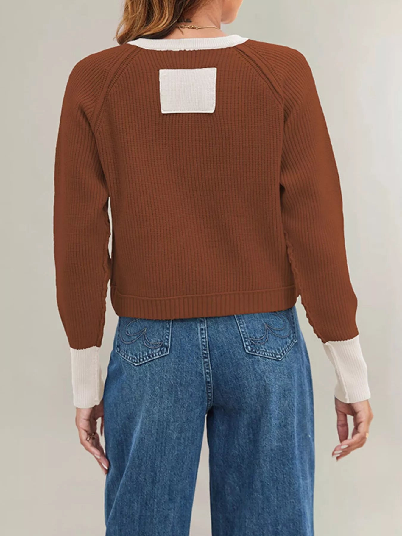 On-model back view of the rust brown ribbed cardigan with cream trim at the cuffs