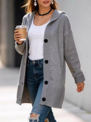 Long gray hooded knit cardigan with black buttons worn open over a white top