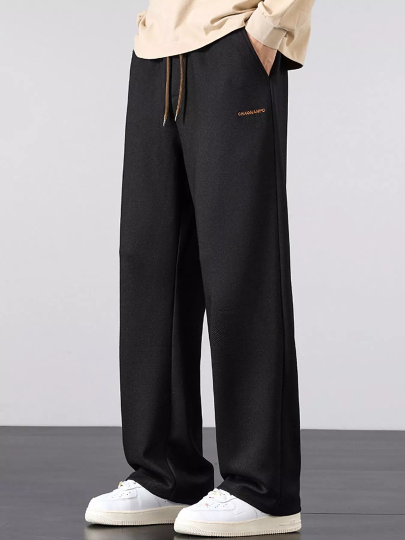 Men's black loose fit casual pants with a drawstring waist and pockets.