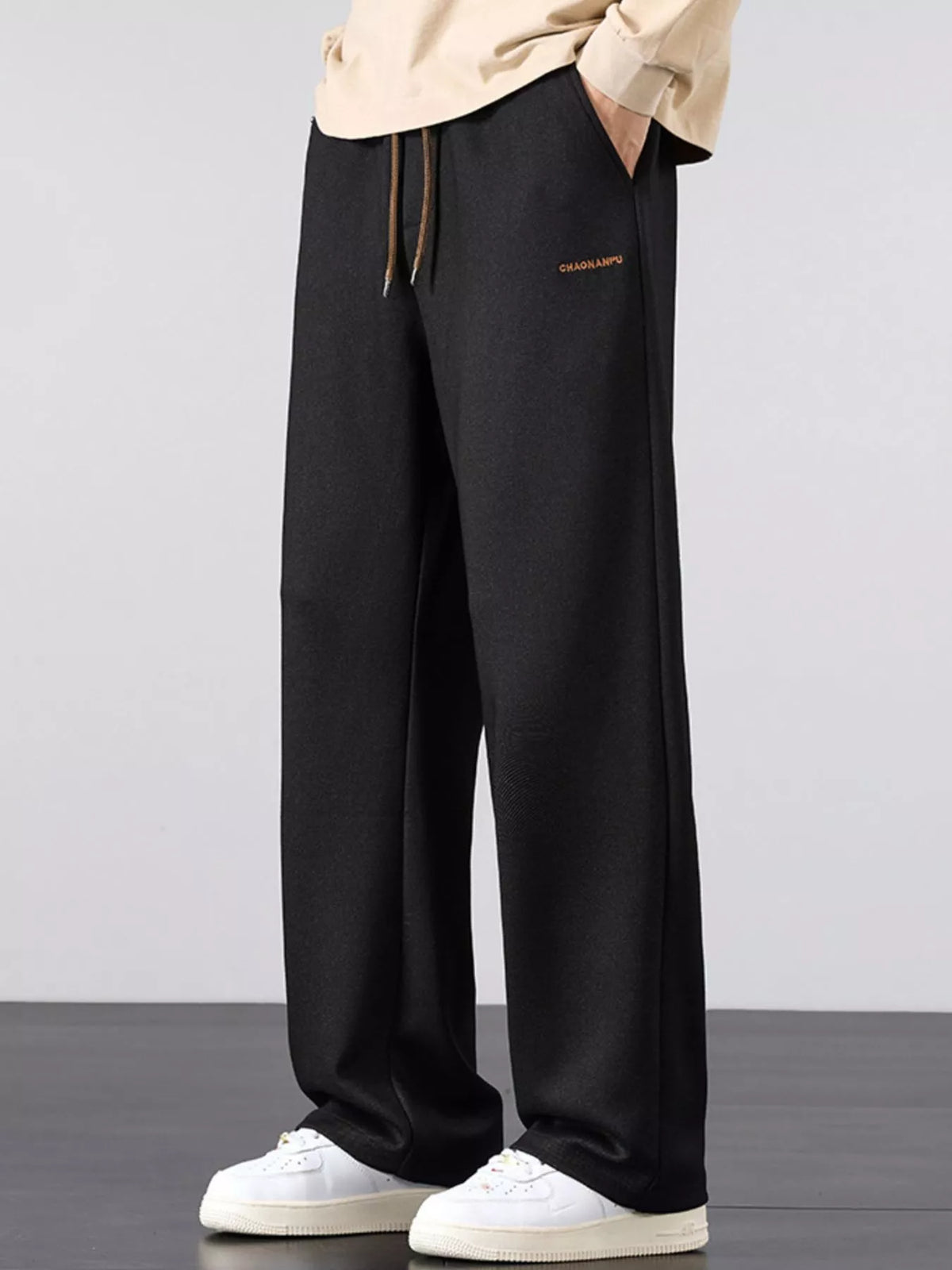Men's black loose fit casual pants with a drawstring waist and pockets.