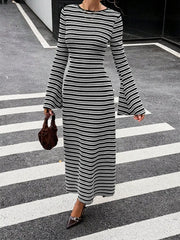 On-model full length front view of the black and white striped sweater dress on a crosswalk