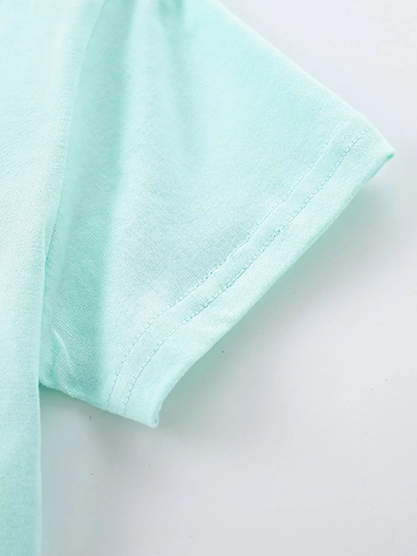 Close-up of mint blue children's short sleeve hem with neat double stitching