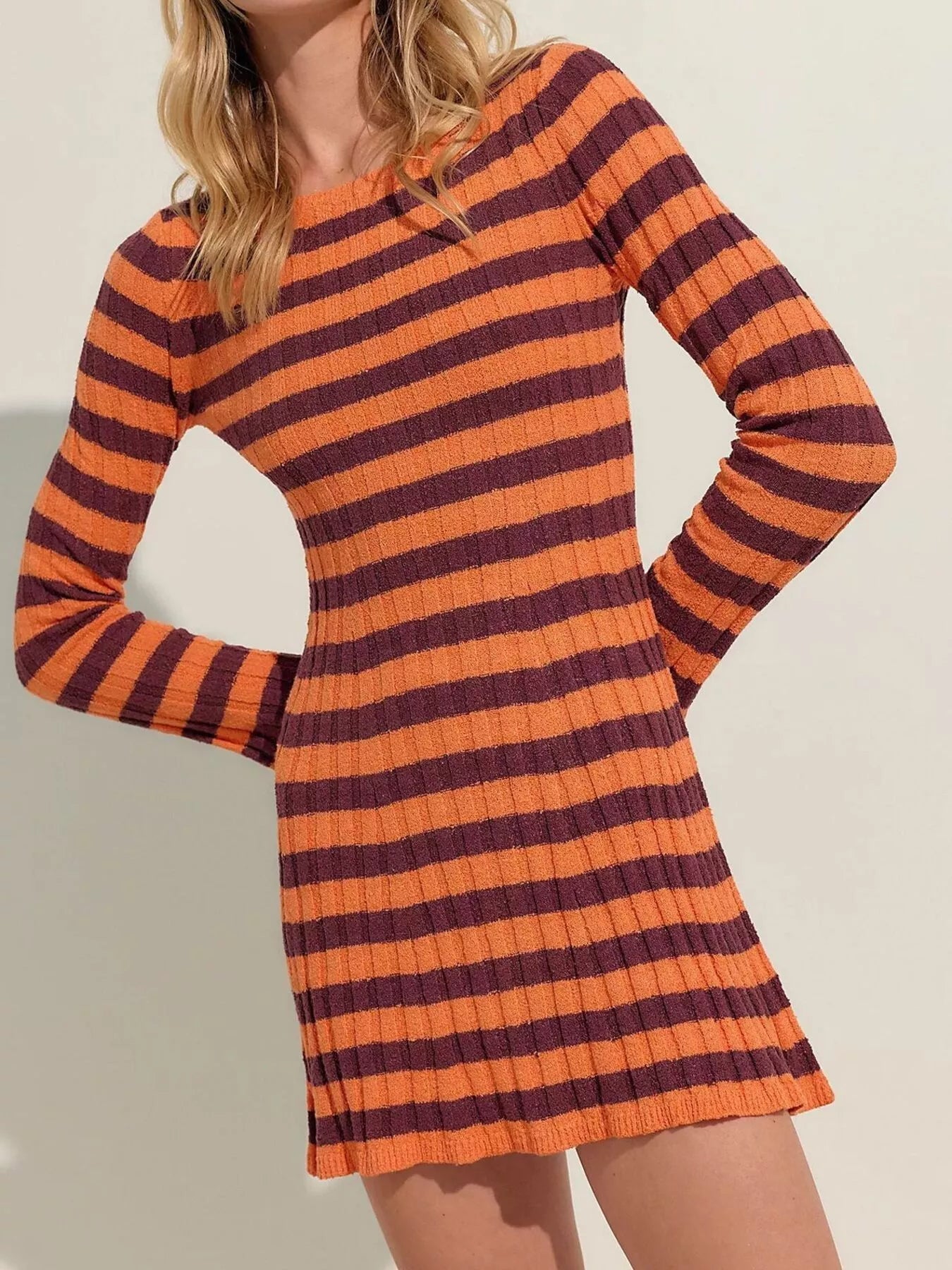 Orange striped ribbed knit long sleeve sweater dress in a front view with hands on hips