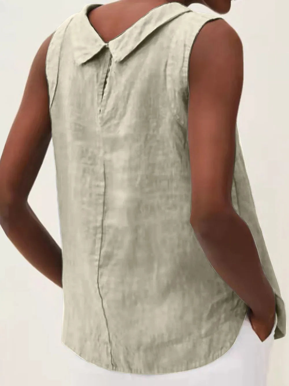 Back view of a sleeveless light-colored top with a pointed collar and button-front closure