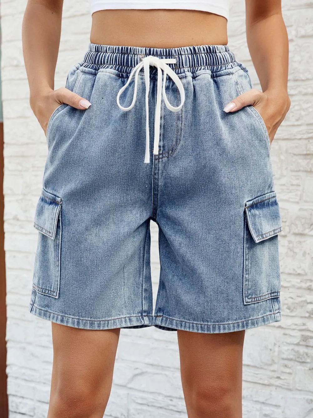 Women's dusty blue denim shorts with a drawstring waist and pockets.