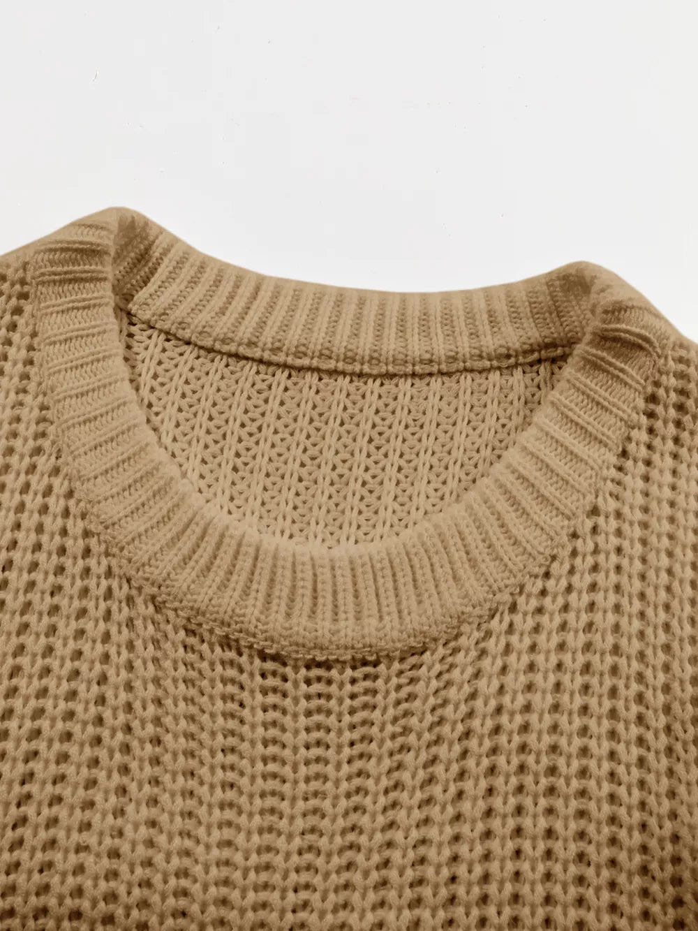 Close view of taupe ribbed knit sweater showing round neckline and open knit texture.