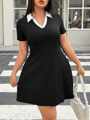 Front view of black plus size mini dress with white contrast collar holding a bag
