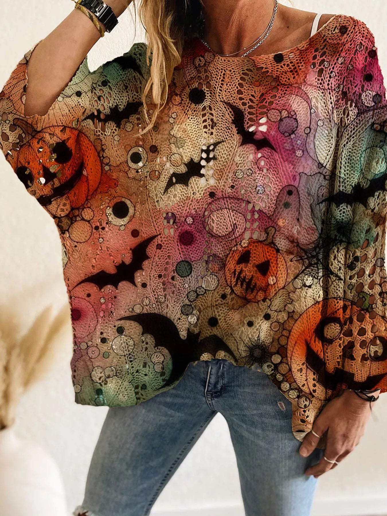 Front view of a multicolor openwork knit cover up with jack o lanterns, bats, and ghosts.