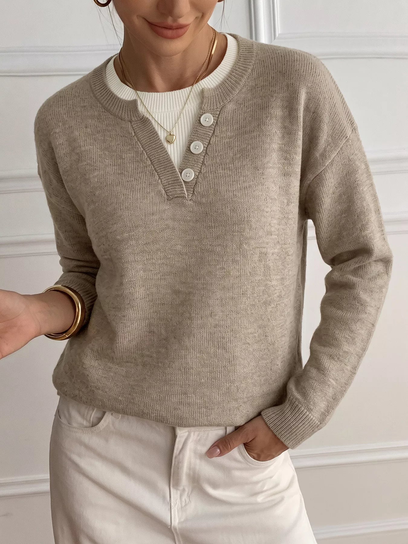 Khaki dropped shoulder sweater with V neck button placket over white ribbed top, front