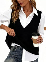 Black V neck knit sweater vest over white shirt, model holding coffee and lifting hem