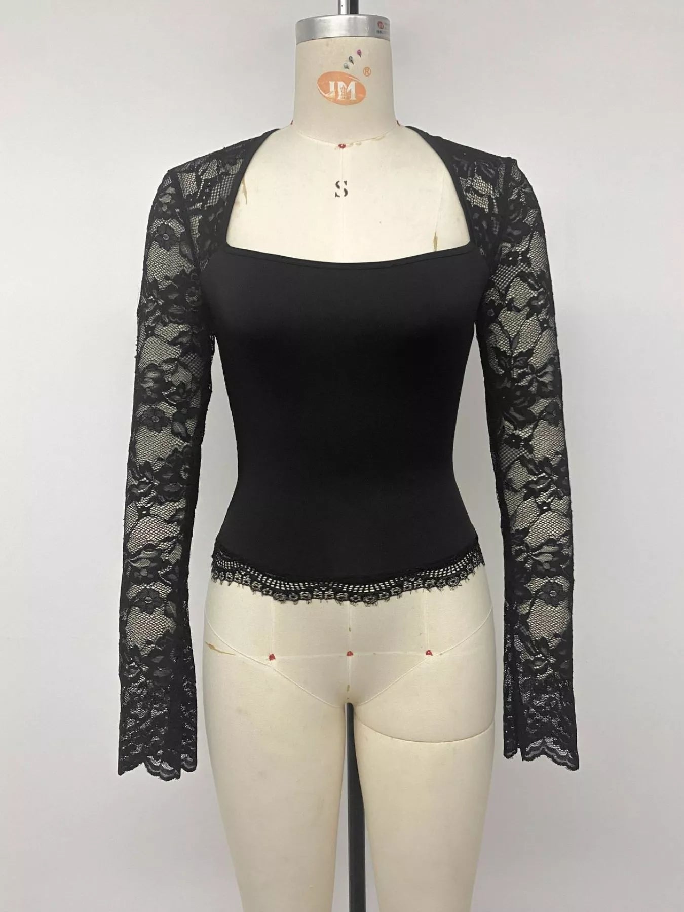 Black square-neck top with sheer floral lace long sleeves and scalloped lace hem, displayed on a mannequin