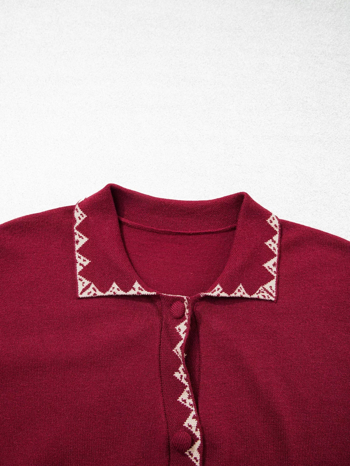 Close view of the burgundy cardigan collar with cream zigzag trim flat lay