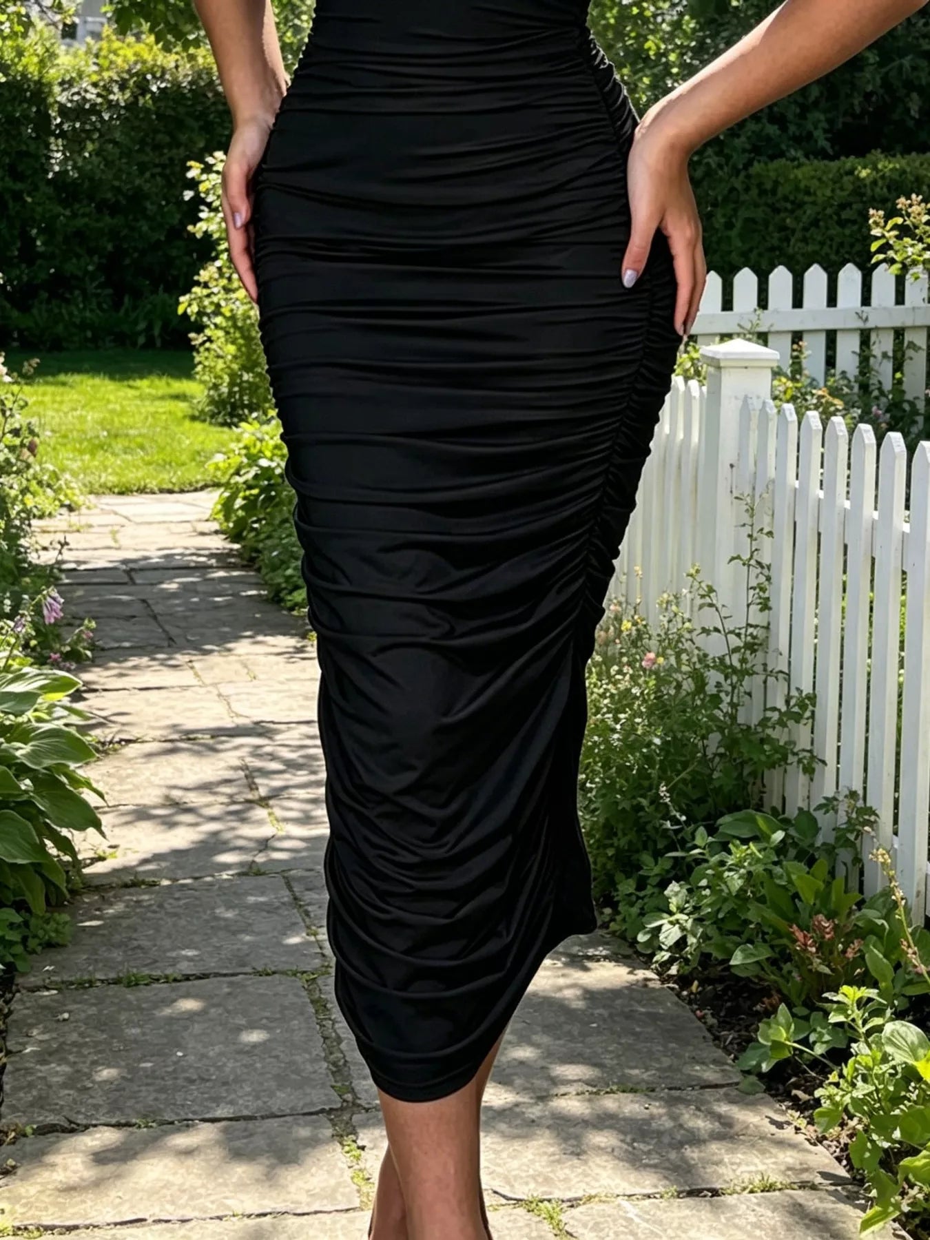 Close view of black ruched tube bodycon midi dress skirt showing ruched fabric